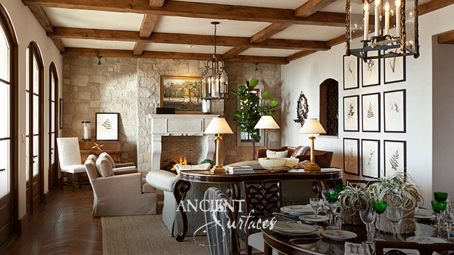 Carved limestone fireplace mantel set into a coursed limestone feature wall beneath reclaimed timber beams