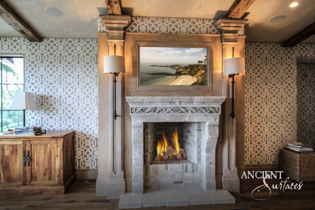 Reclaimed limestone fireplace surround with a carved frieze framed by pale millwork in a living room