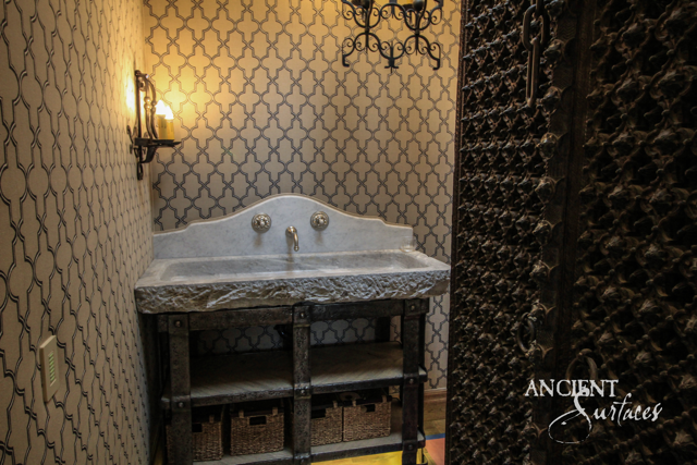 Monolithic limestone sink with a chiseled edge and shaped backsplash resting on an iron washstand