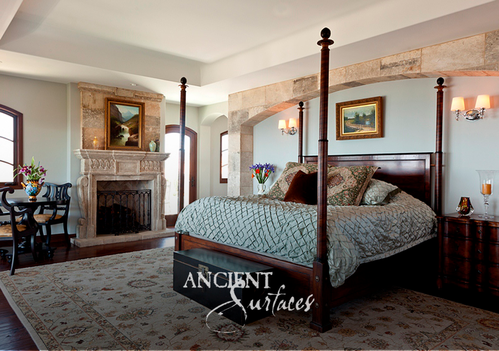 Reclaimed limestone bedroom mantel with a patterned frieze beside an antique limestone arch